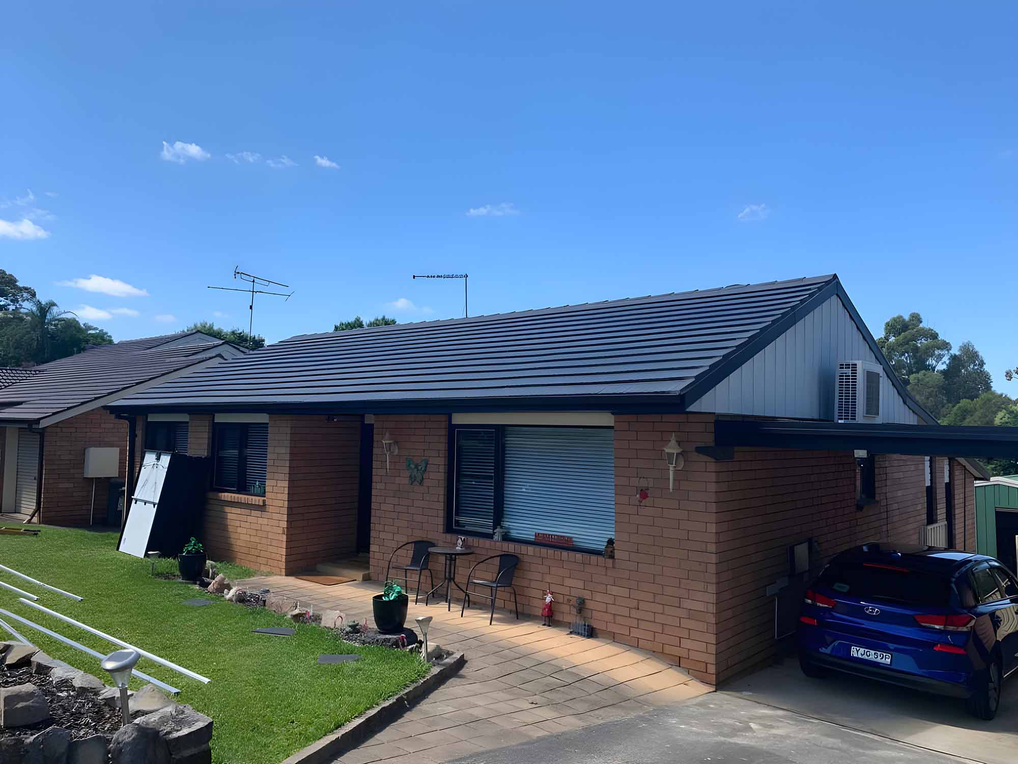 Brick home with a dark charcoal tiled roof and a car in the driveway