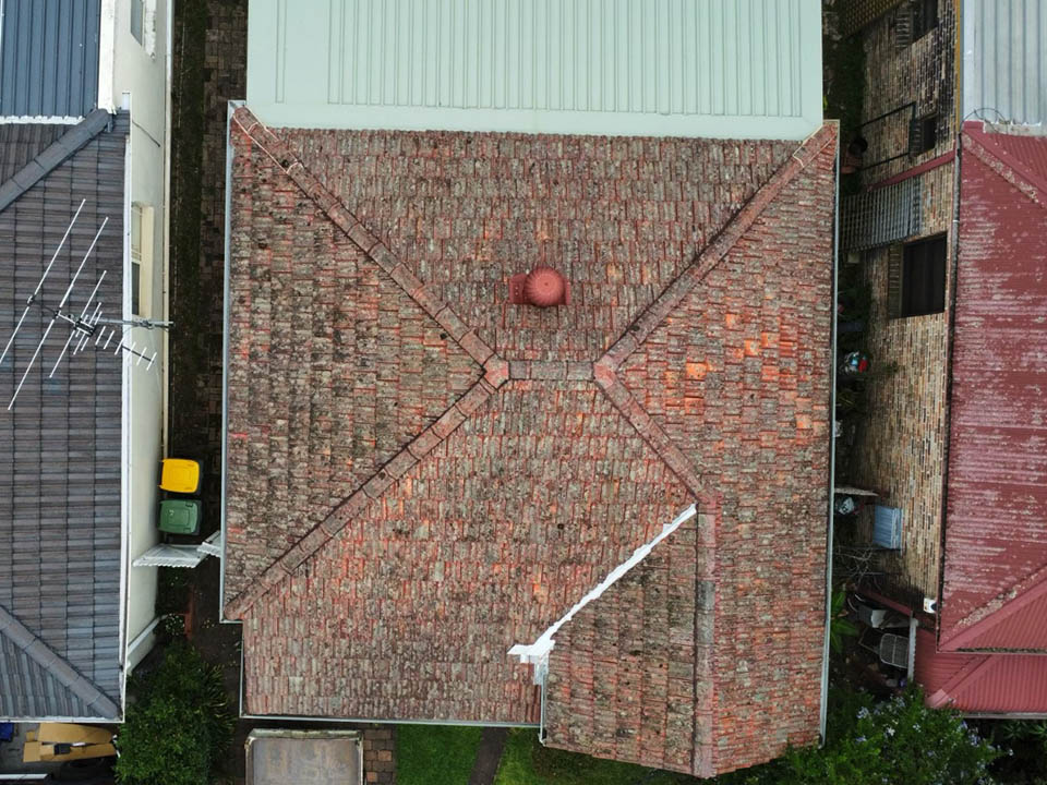 Before: aerial view of a weathered, faded red tiled roof